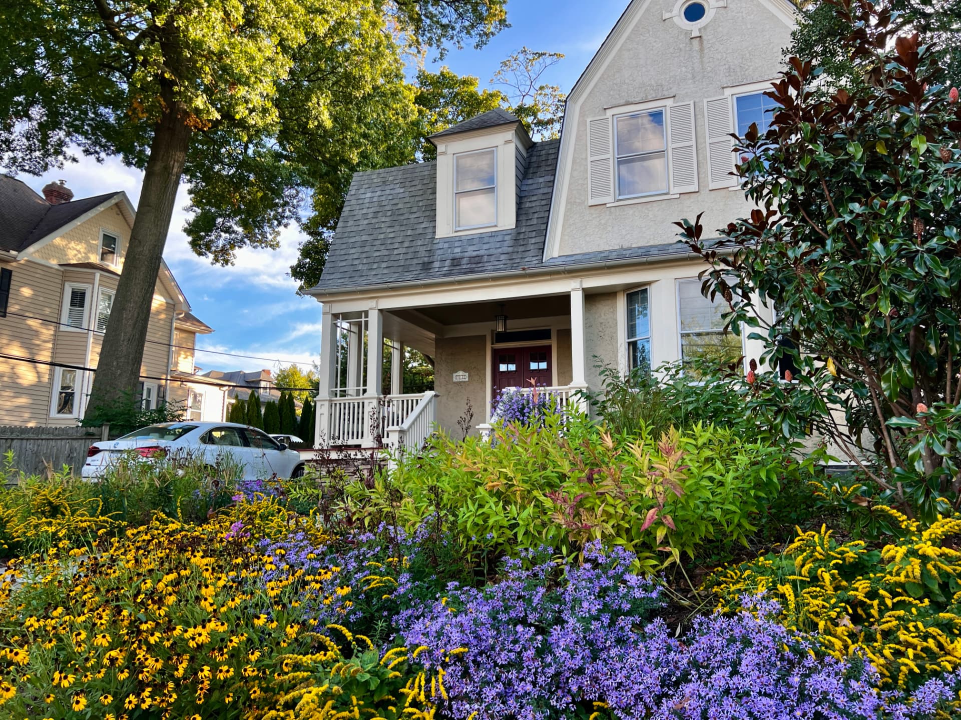 Evening light on the Bryn Mawr townhome with golden rudbeckia and purple blooms along the walk