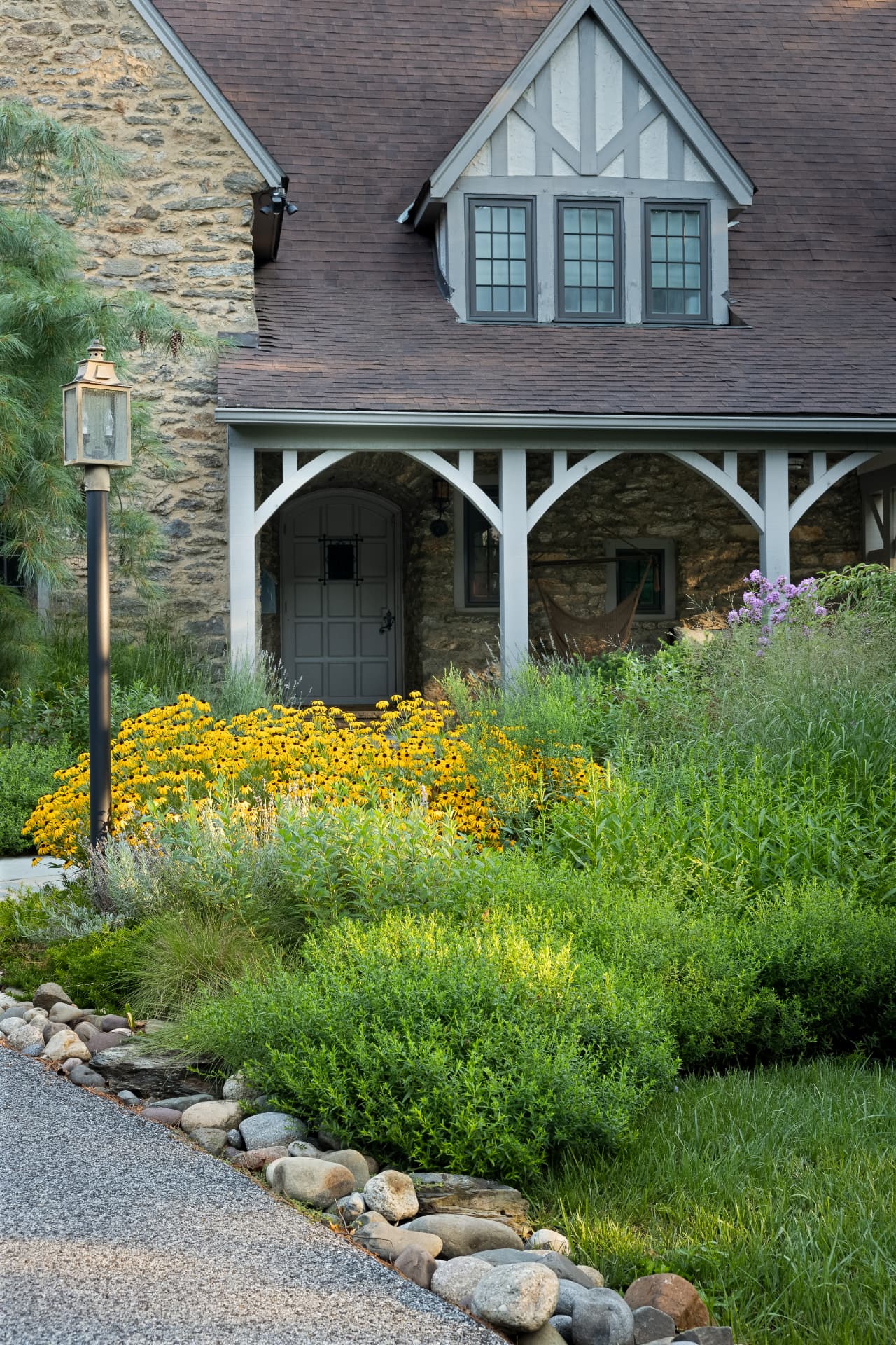Stone entry porch with lantern, black-eyed Susans, and a small stream along stone edging