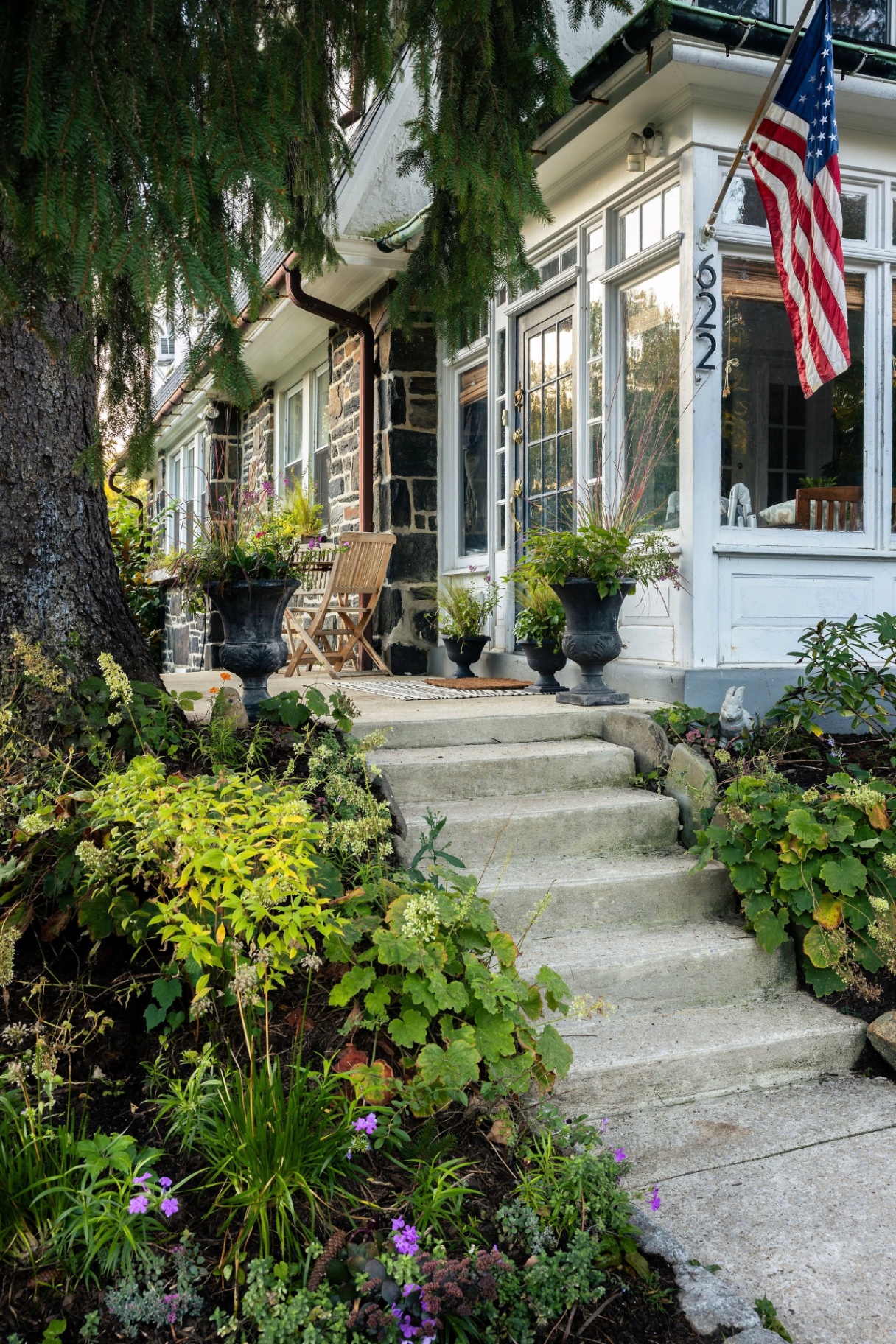 Steps to the front porch lined with urns, coral bells, and soft native planting