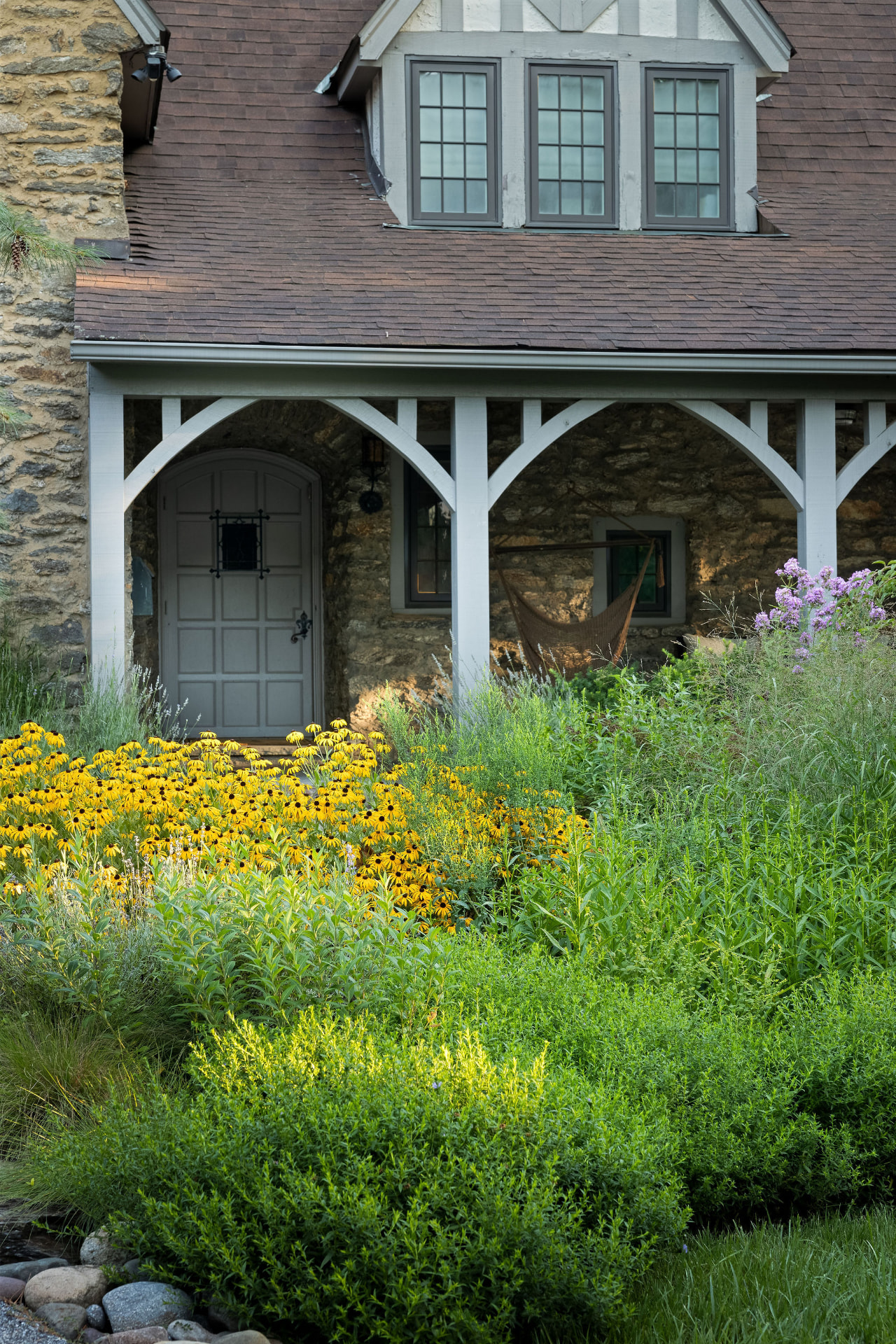 Close view of the stone entry porch with black-eyed Susans and phlox in the foreground