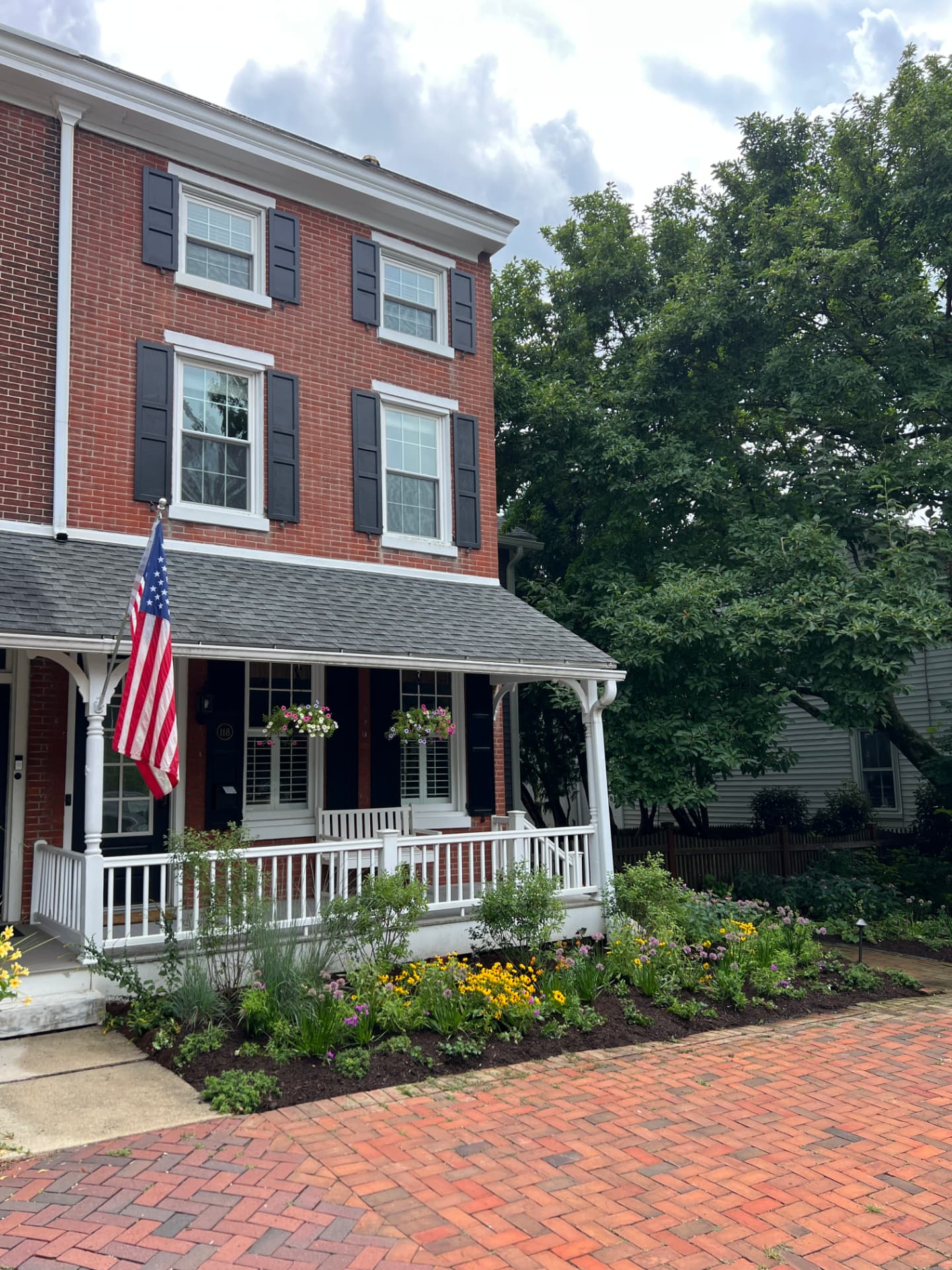 After: angled view of the porch, brick walk, and full layered front planting