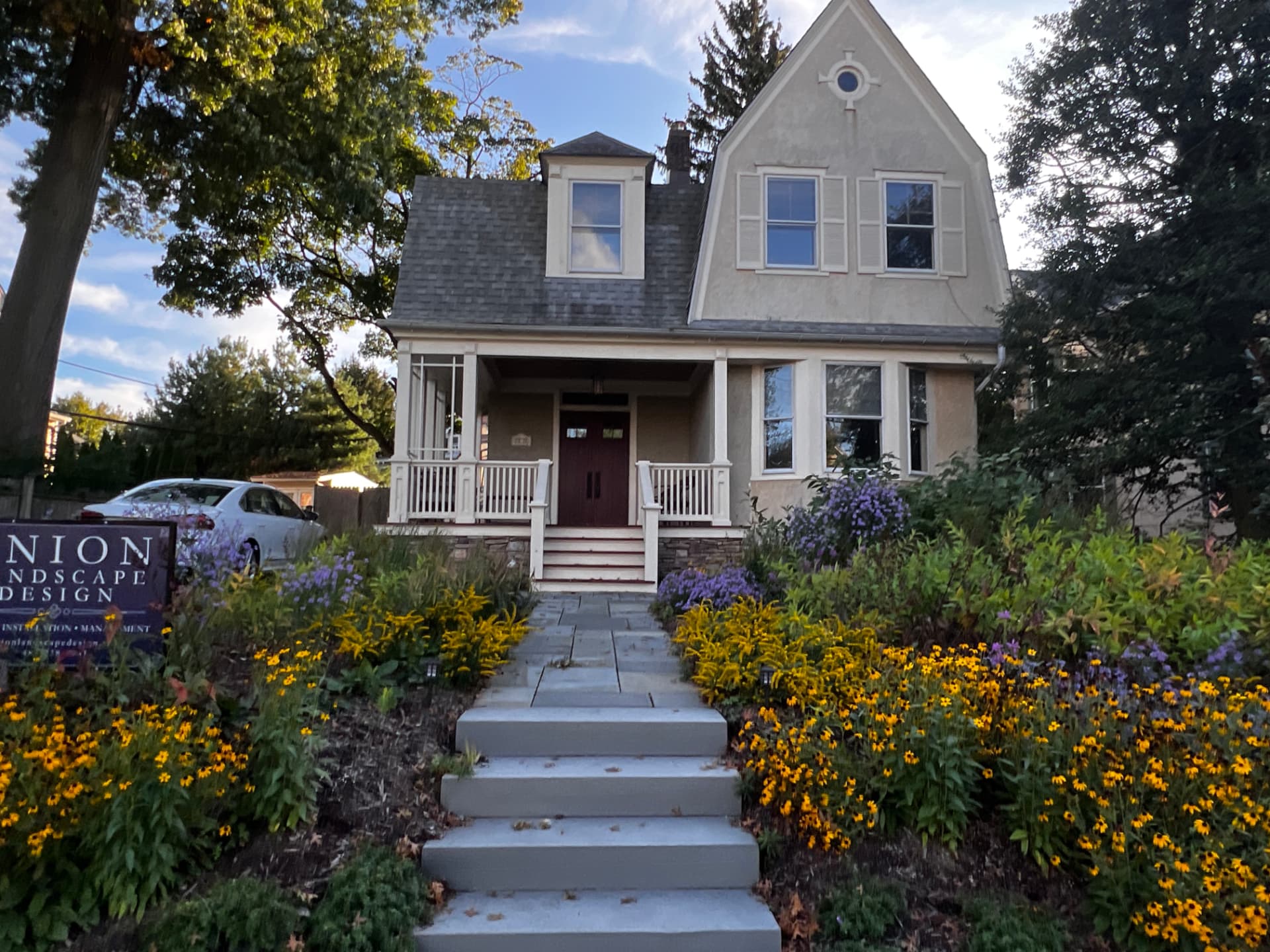 Bluestone front steps lined with yellow rudbeckia and a Union Landscape Design sign