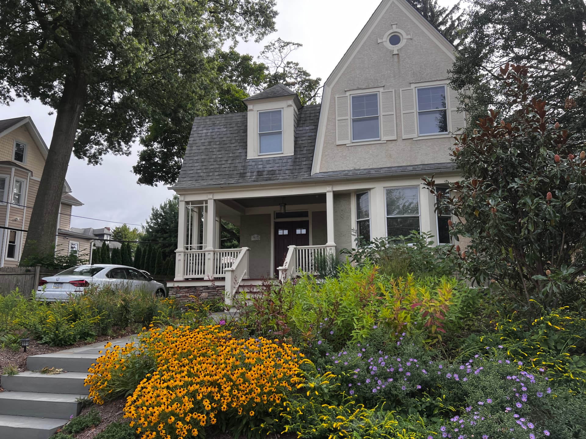 Wide view of the Bryn Mawr townhome front yard filled with yellow rudbeckia and purple asters